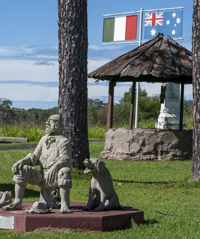 Il Pioniere memorial statue at the Park of Peace, seated pioneer figure with his dog, Italian and Australian flags above